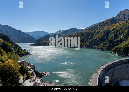 Panorama View Of Kurobe Lake Dam In Toyama. River Dam And Tateyama Mountains On Sunny Day. Stock Photo