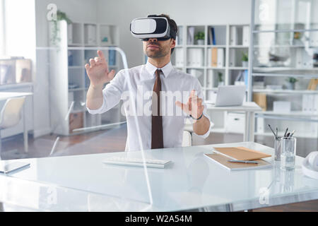 Elegant businessman in vr headset pointing at transparent computer screen Stock Photo