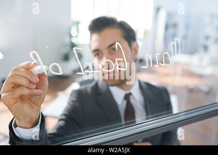 Business coach with white highlighter writing down on board Stock Photo