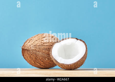 Coconut with half on wooden table against blue background Stock Photo