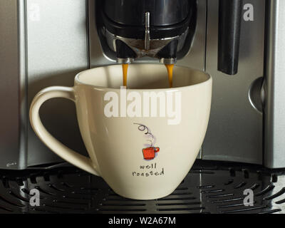 Coffee being dispensed from a bean to cup coffee machine in to a white cup Stock Photo