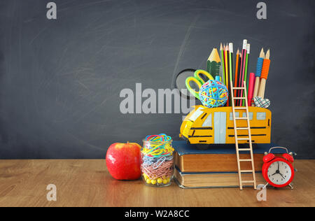 education and back to school concept. pencils stand as bus over wooden desk infront of classroom blackboard Stock Photo