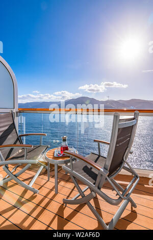 Refreshing drink on a balcony with outdoor chairs and table on a cruise vacation. Sea background. Stock Photo