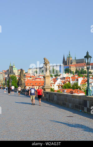 Prague, Czech Republic - June 27th 2019: Tourists on beautiful Charles Bridge in the center of Czech capital. Prague Castle in background. Famous tour Stock Photo