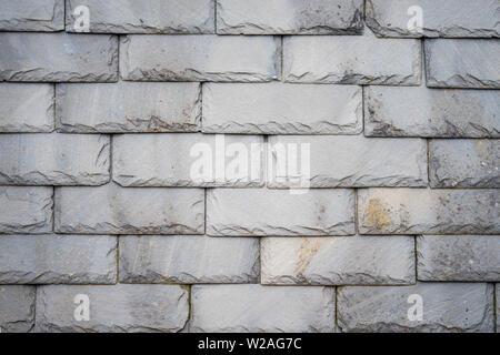 Part of an olf weathered slate tile roof as a background.Closeup detail pattern of grey stone tiles Stock Photo