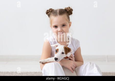 Children, pets and animal concept - Child girl play with her Jack Russell Terrier puppy indoors Stock Photo