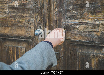 Woman opening very old wooden door in the house. Stock Photo