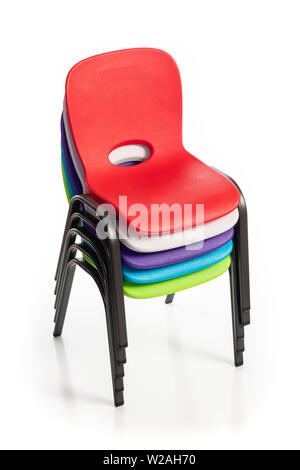 Plastic chairs for children of diverse colors stacked up on a white background. Stock Photo