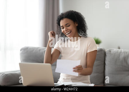 Excited overjoyed black girl student read good news in letter Stock Photo