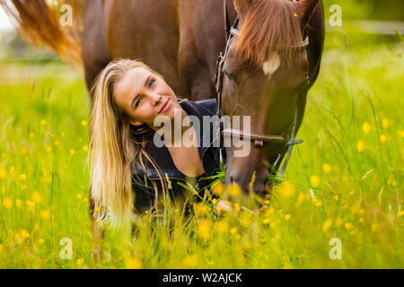 Close-up of woman feeding her arabian horse with snacks in idyllic meadow Stock Photo