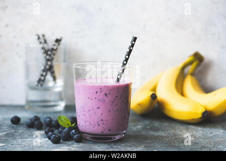 Fresh blueberry blackberry and banana smoothie in glass with drinking straw, toned image. Copy space for text Stock Photo