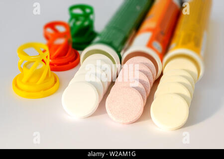 Three kinds of soluble effervescent vitamins spilled out of their plastic bottles on a white background. Under a sunlight. Vitamins and nutritional su Stock Photo