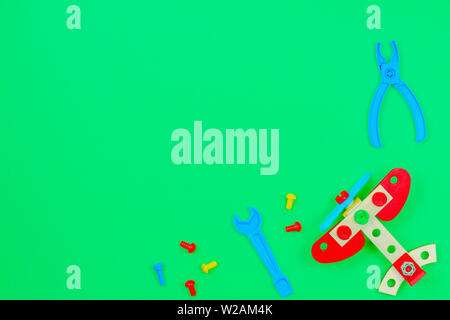 Toy wooden plane, bolts and toys tools on green background Stock Photo