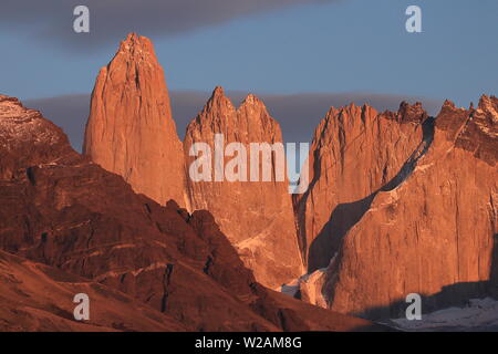 Orange sunlight at sunrise over Las Torres in the Torres del Paine National Park, Magallanes, Chilean Patagonia. Stock Photo