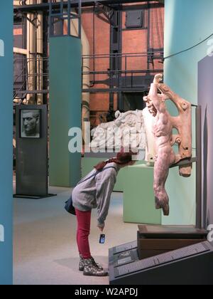 A female visitor studies a Roman sculpture in the industrial power plant surroundings of the Montemartini Museum Stock Photo