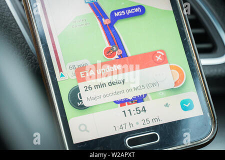 London, UK - June 11, 2019 - standstill traffic jam on m25 motorway; smartphone screen with GPS navigation showing delay Stock Photo