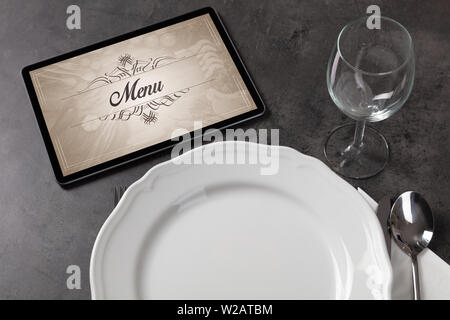 Tablet with stylish restaurant logo and laid table Stock Photo