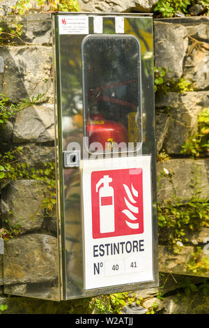 TREMZZO, LAKE COMO, ITALY - JUNE 2019: Metal box holding a fire extinguisher for emergency use in the gardens of the Villa Carlotta on Lake Como. Stock Photo