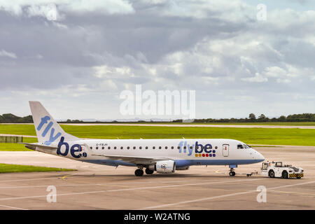 CARDIFF WALES AIRPORT - JUNE 2019: Flybe Embraer E175 plane being pushed by an airport tug for departure from Cardiff Wales Airport. Stock Photo