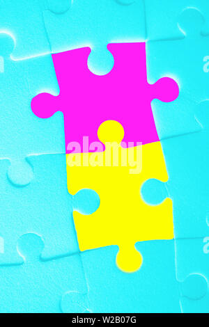 Multiple white puzzle pieces put together with two bright pieces. View from above. Stock Photo