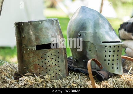 Knightly medieval metal two helmets on the stand. Old dark ages armor and equipment for knights head protection in battle. Historical and medieval Stock Photo