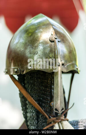 Medieval old metal helmet on the stand. Knightly armor and equipment for head protection in battle. Historical and medieval age concept. Close up Stock Photo