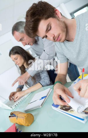 male student with others writing notes in the classroom Stock Photo