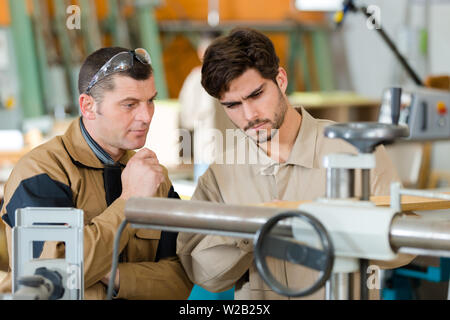 engineer training apprentices on machine Stock Photo