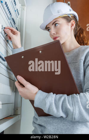 female electrician inspecting fuse board Stock Photo