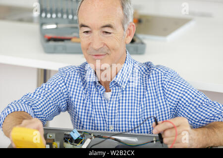 senior man testing appliance with multimeter Stock Photo