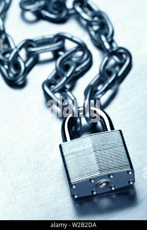 Security concept showing tough strong steel padlock and chain on scratched steel surface Stock Photo