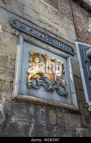 Wooden wall plaque with coat of arms by the St John's Street entrance to Cathedral Close, Salisbury, a cathedral city in Wiltshire, south-west England Stock Photo