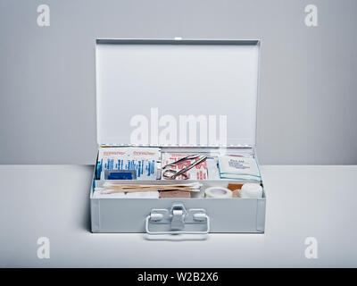 First aid kit packed with medical supplies on grey background Stock Photo