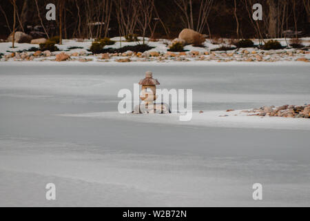 Japanese lantern statue frozen in the middle of a pond Stock Photo