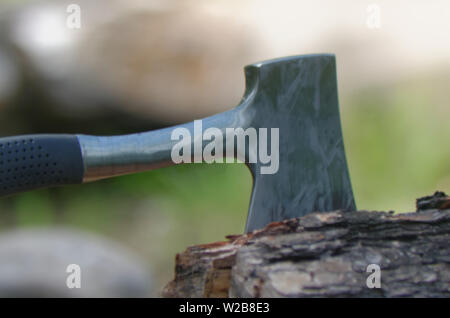 A hatchet with blade buried in a log after being used to chop fire wood Stock Photo