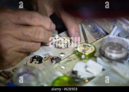 Close up of a watchmaker's hand is repairing small watch with tool. Stock Photo