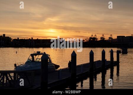 boat moored at a pier with the Port of Los Angeles in the background during sunset Stock Photo