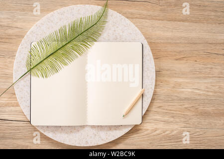 top view of open notebook with leaf and pencil on wooden table with copy space.eco sustainable concept Stock Photo