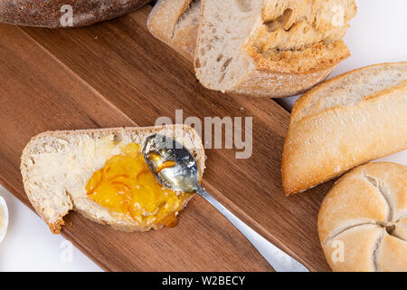 smearing orange marmalade on homemade bread. Stock Photo