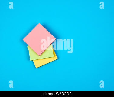 multicolored empty paper square stickers on blue background, copy space Stock Photo
