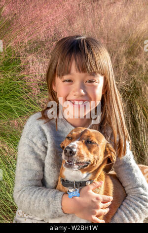 Seven year old girl laughing with her dog in the park Stock Photo