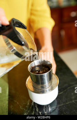 Person making delicious strong morning coffee in Vietnamese press Stock Photo