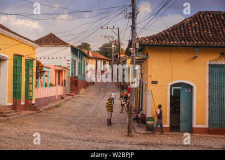 Cuba, Trinidad, Man with stick reaching up to turn on the street lamp Stock Photo