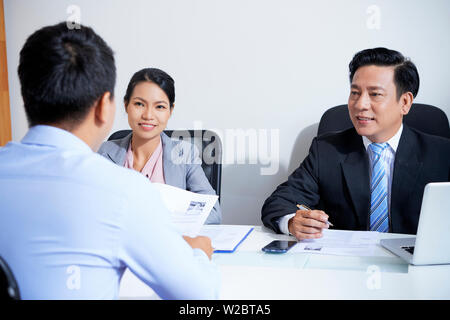 Young applicant talking to smiling human resources managers at office meeting Stock Photo