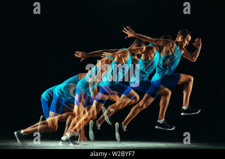 Professional male runner training isolated on black studio background in mixed light. Man in sportsuit practicing in run or jogging. Healthy lifestyle, sport, workout, motion and action concept. Stock Photo