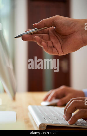 Hand of businessman with pen pointing at computer screen of software developer and explaining task Stock Photo