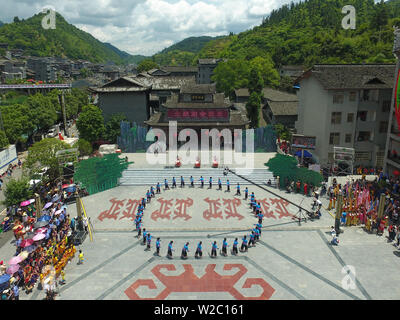 (190708) -- BEIJING, July 8, 2019 (Xinhua) -- Aerial photo taken on June 6, 2019 shows people of the Tujia ethnic group dancing to celebrate the Sheba Day in Xichehe Town of Longshan County, central China's Hunan Province. Located in central China, Hunan Province is well-known for its varied topography. It abuts the Dongting Lake to the north, and the east, south and west sides of the province are surrounded by mountains, with Wuling and Xuefeng Mountains to the west, Nanling Mountain to the south, Luoxiao and Mufu Mountains to the east. The Xiangjiang, Zijiang, Yuanjiang and Lishui Rivers con Stock Photo