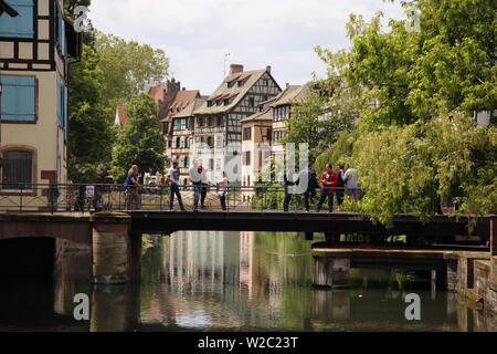 Tourists crossing one of the many bridges in Petit France, Strasbourg France Stock Photo