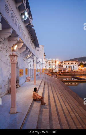 India, Rajasthan. Pushkar, Man sitting on Ghat steps at twilight Stock Photo