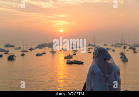 Indian woman looking out over Mumbai harbour by Gateway to India at sunrise, Mumbai, Bombay, India Stock Photo